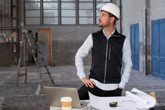 Male architect contemplating while standing at table in building