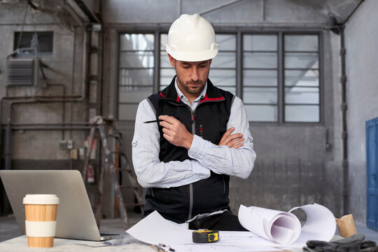 Male engineer thinking while analyzing blueprint on table in building - Powered by Adobe