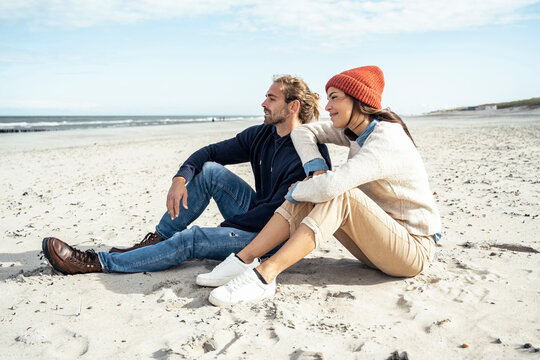 Young couple sitting together on beach sand