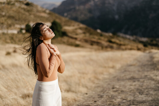 Young woman with eyes closed standing in field during sunset