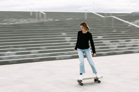Young woman skateboarding near steps