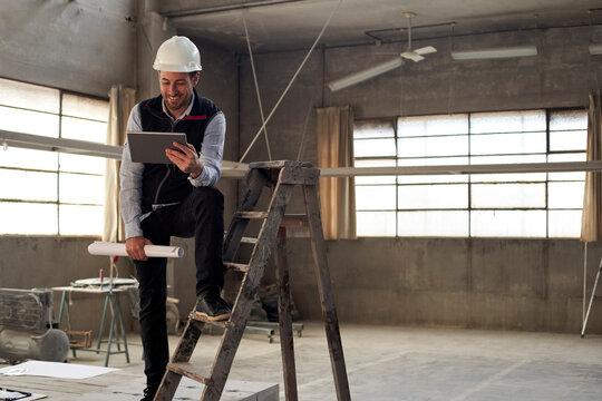 Smiling male building contractor using digital tablet while standing inside site