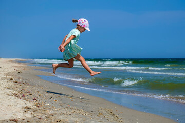 Baby girl skipping along the sea beach