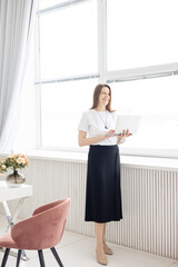a young female coach works in a home office in a light interior conducts a presentation with laptop, the concept of remote work