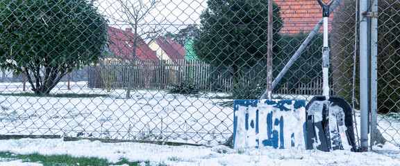 Schneeschieber an einem Zaun im Winter