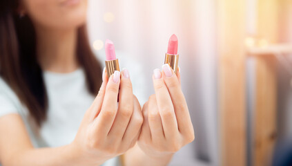 Woman is choosing new lipstick applies colour on skin of hand