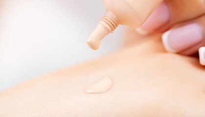 Macro photo beauty, young woman chooses foundation for skin of face, selects tone of cream on hand