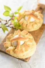 Homemade sweet Italian Easter Bread Rings with eggs called puddica in Puglia, on an old wooden cutten board with spring twig, close-up.