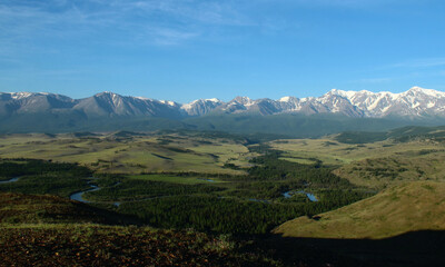 Naklejka premium Alpine snow-covered North-Chuya ridge in the Kurai steppe in Altai, in the Chuya river valley, hills and forest, summer, sunset, sunny