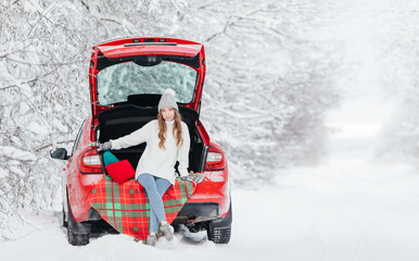 Woman with hot coffee in her hands sits in a red car on a snowy winter day