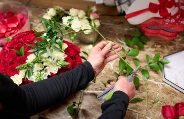 Florist preparing flowers for Flower box with red roses and white flowers on the table