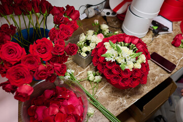 Flower box with red roses and white flowers on the table, flower box assembly process