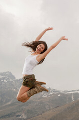 Giovane donna salta felice con le braccia in alto