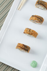 Fried crispy unagi rolls in a white ceramic platter