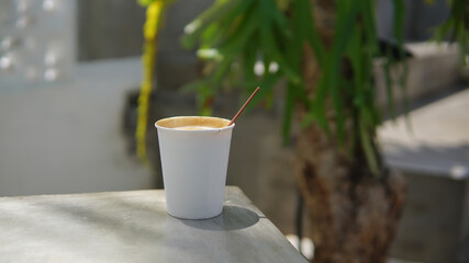Coffee latte in a white paper cup on a concrete table
