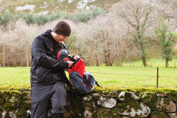 Fototapeta na wymiar hiker sitting taking a break and looking inside his backpack in the field. healthy lifestyle and sport.