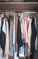 A wardrobe with clothes on hangers and on a shelf. Side view. The concept of storing clothes.