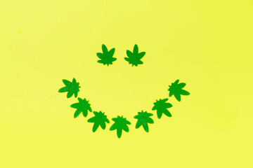 Smile made from green cannabis leaves. Smiling face symbol made with marijuana leaves. 