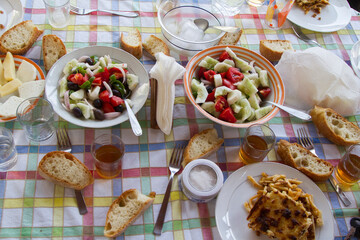 Naxos, Cyclades, Greece   07.31.16 
Sunday table with Naxos products, bread, greek salad, gruyere, pastitsio and white wine.in a cart, colored tablecloth