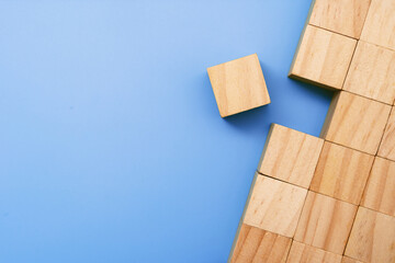 One Wooden Block Isolated From the Rest of Wooden Block Group on Blue Background.