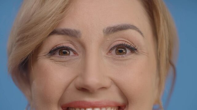 Very close-up of a young woman's smiling eyes.Studio shot isolated on blue background.