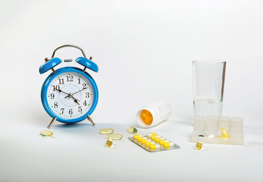 Time To Take Your Pills. An Alarm Clock On A White Background Shows The Time Of Taking Medication, And Next To It - Medical Pills.	
