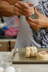 Haciendo repostería en casa. Manos Colocando bísquets  en charola para hornearlos en la estufa.