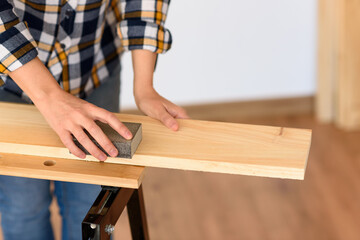 Woman sanding wood on a workbench with white background indoor.
