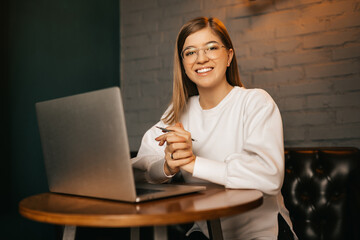 The girl smiles at the camera at the computer. Blurred background. Isolated background.