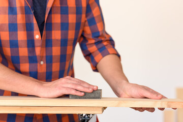 Fototapeta na wymiar Close up shot of a man at home sanding wood on a workbench.