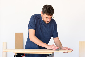 man at home sanding a wood on a workbench