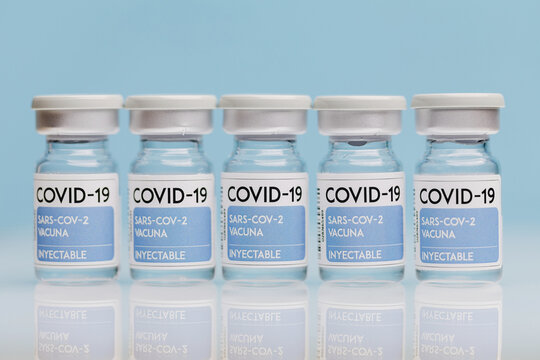 Glass vials with vaccine from COVID 19 placed on table in row on blue background