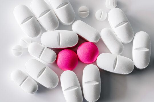 Assorted colorful and white pills and capsules placed on white table