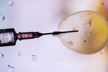 Closeup of needle of syringe filled with vaccine from virus injected in cell on blurred background