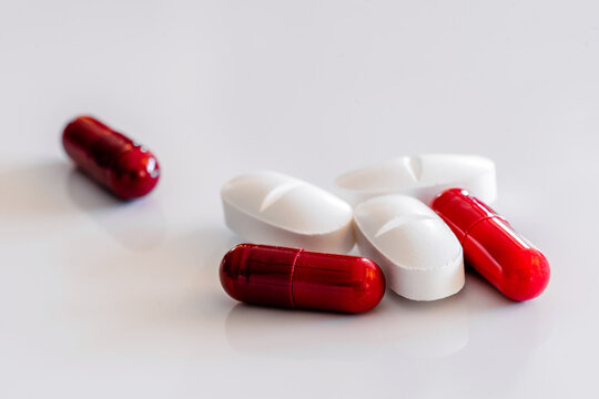 Assorted colorful and white pills and capsules placed on white table