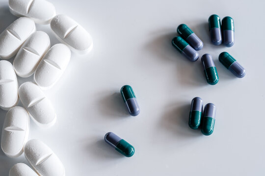 Top view of assorted colorful and white pills and capsules placed on white table