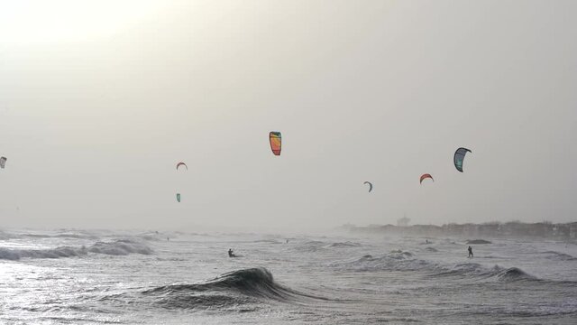 des kitesurfers en pleine action au ralenti au milieu des vagues, avec des voiles dans le ciel
