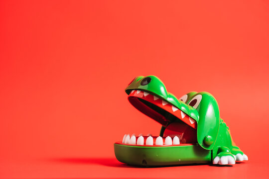 Plastic crocodile teeth toy of green color placed on table on red background in studio