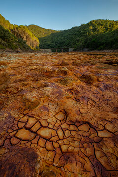 Amazing view of river with clear water and orange bottom on sunny day in Minas de Rio tinto with mountain landscape on the background