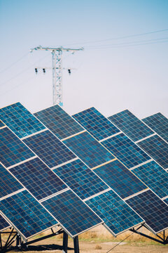 Modern solar panels installed in field against cloudy sky in photovoltaic power station