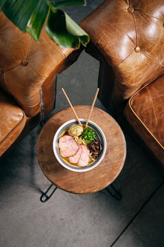 Top view of delicious traditional ramen soup in bowl with chopsticks served on round table