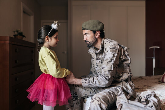 Military father holding hands of small girl before going to defend country