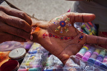Obraz na płótnie Canvas A street artist offering colorful hena painting onf hands, Jaipur, India