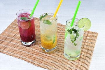 Colorful italian sodas with chopped fruits on white wooden background