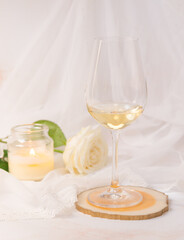 Glass of white wine, rose and candle on a white background. 8th march and valentine's day concept