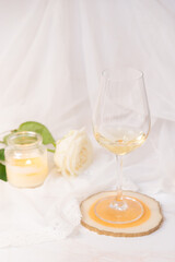 Glass of white wine, rose and candle on a white background. 8th march and valentine's day concept