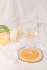 Glass of white wine, rose and candle on a white background. 8th march and valentine's day concept