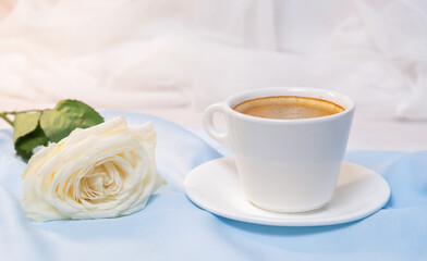 White rose with a Cup of coffee on a blue background. concept of march 8 and valentine.
