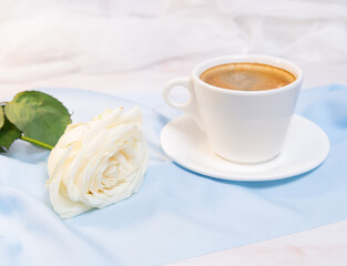 White rose with a Cup of coffee on a blue background. concept of march 8 and valentine.