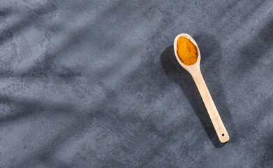 Curcuma longa - Turmeric powder in wooden spoon